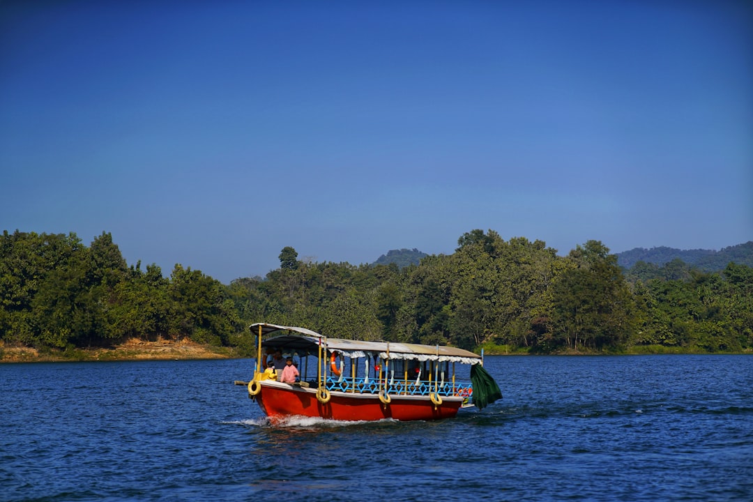 A boat sails on a calm blue lake with trees.