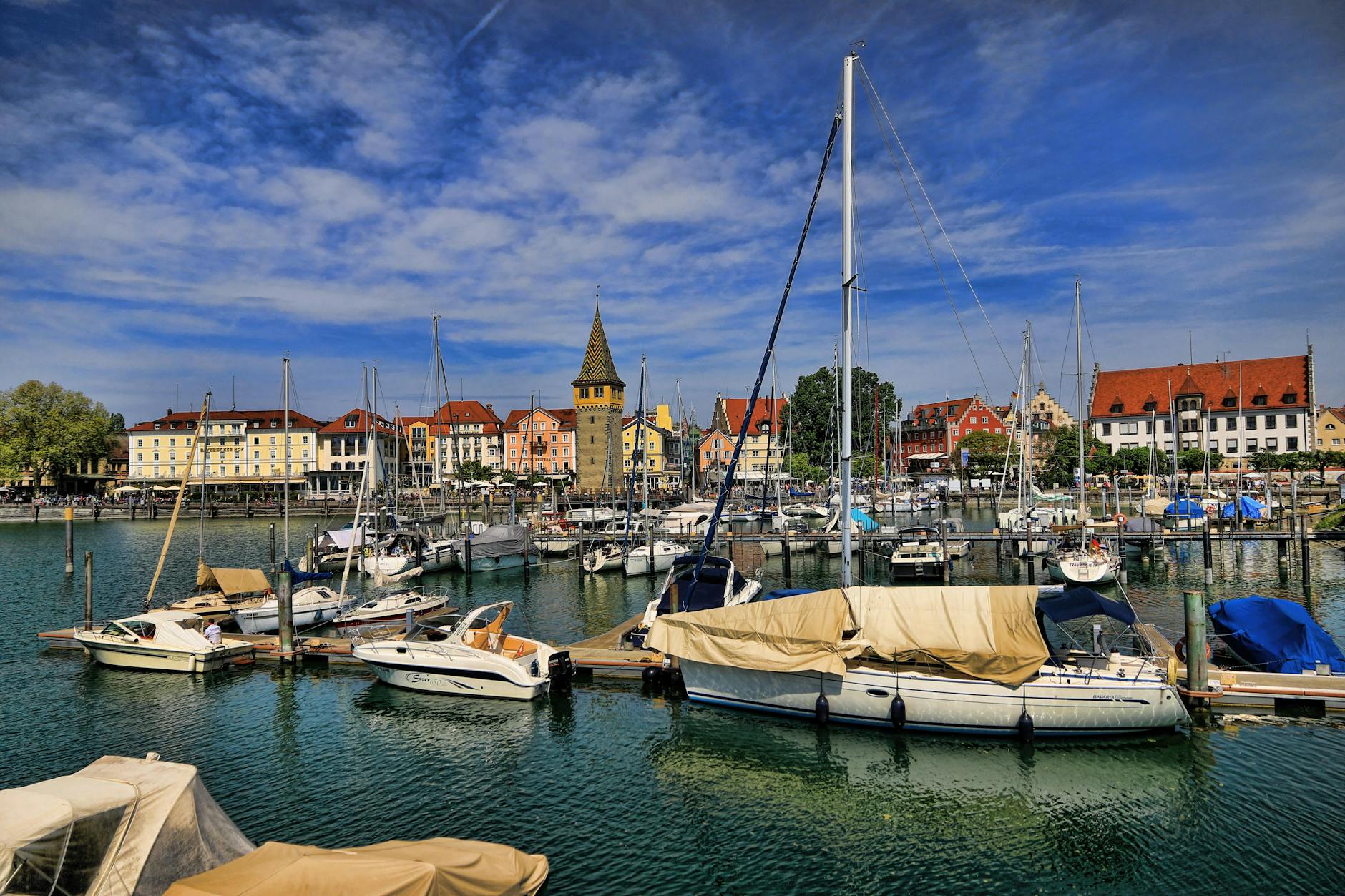 Vibrant view of Lindau harbor showcasing docked sailboats set against a blue sky and charming buildings.