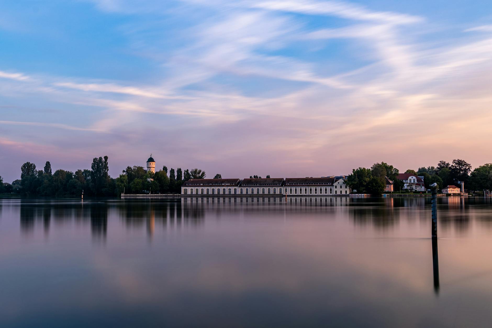 Peaceful twilight over Lake Constance with cityscape and historical building reflections.