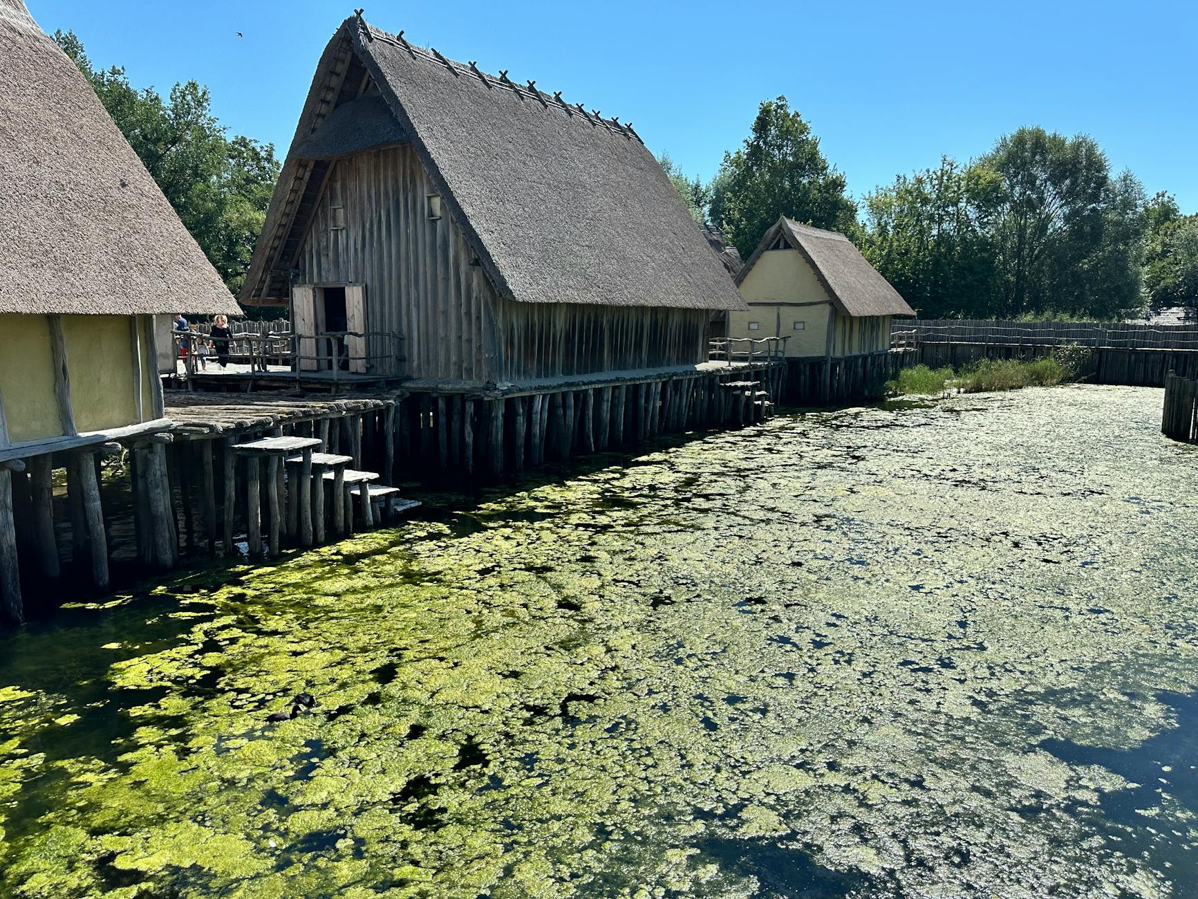 Traditional stilt houses on Lake Constance with a serene water view under a clear blue sky.