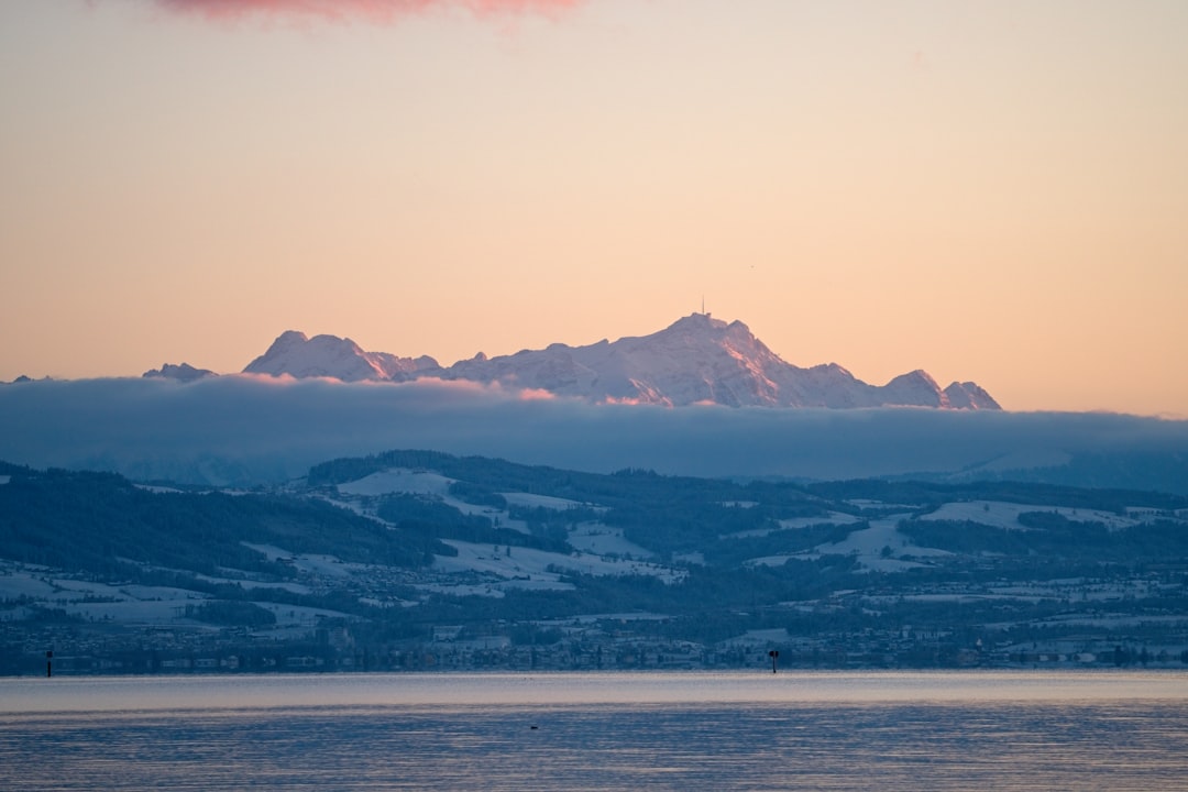 Snow-capped mountains emerge from clouds at sunset