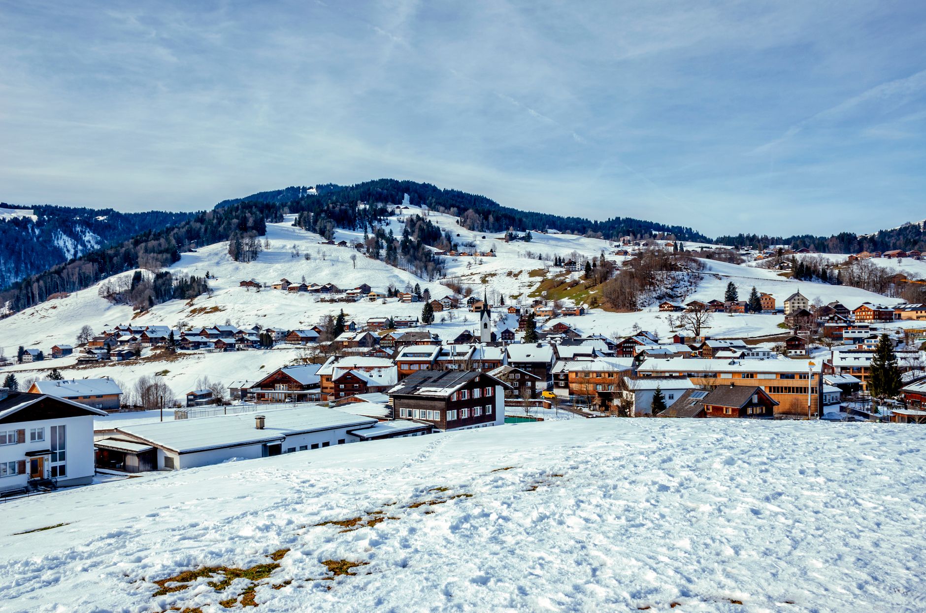A stunning winter landscape of Schwarzenberg with snow-covered houses and mountains in Vorarlberg, Austria.