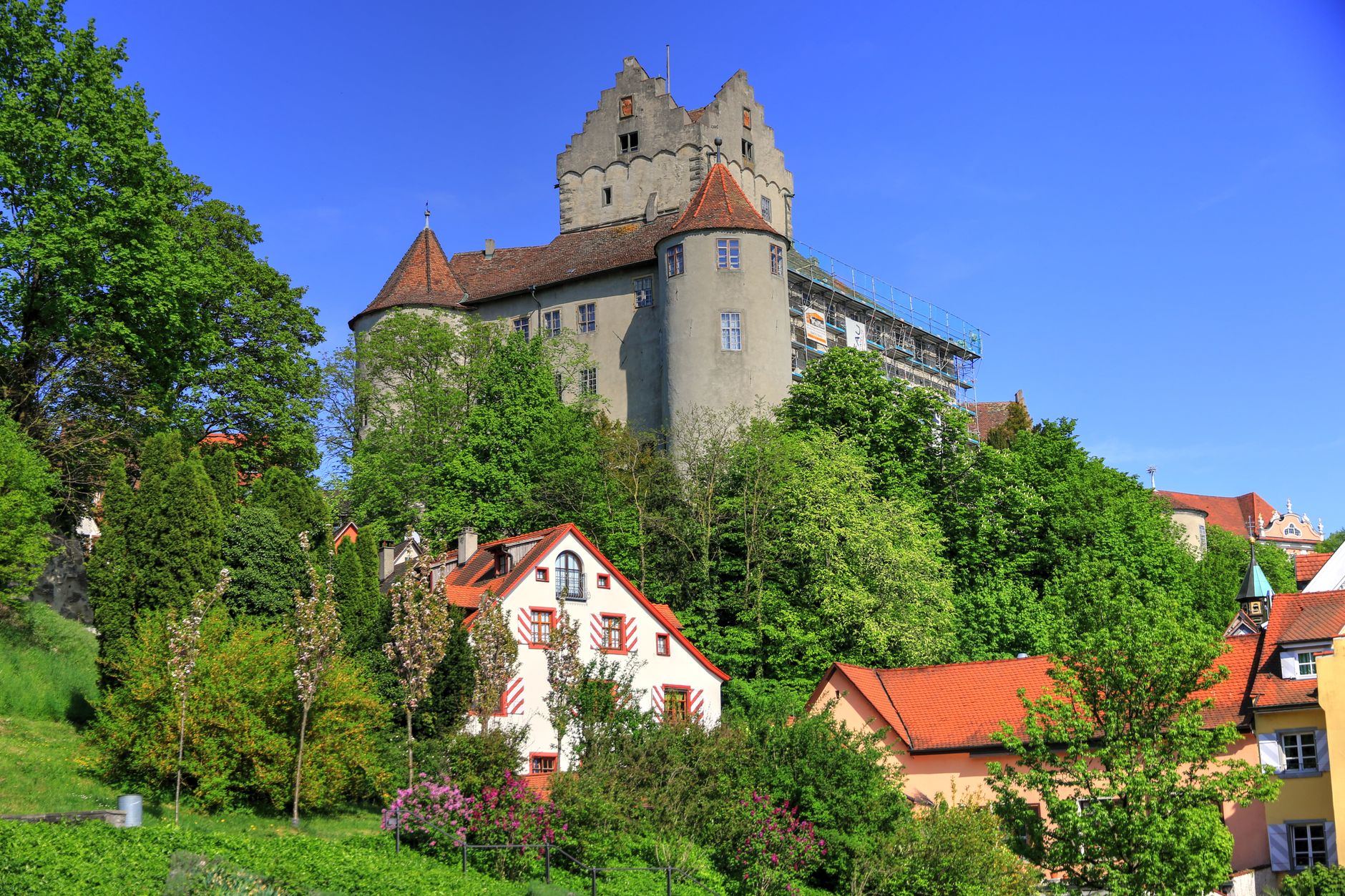 Stunning view of medieval Meersburg Castle surrounded by lush greenery and charming houses.