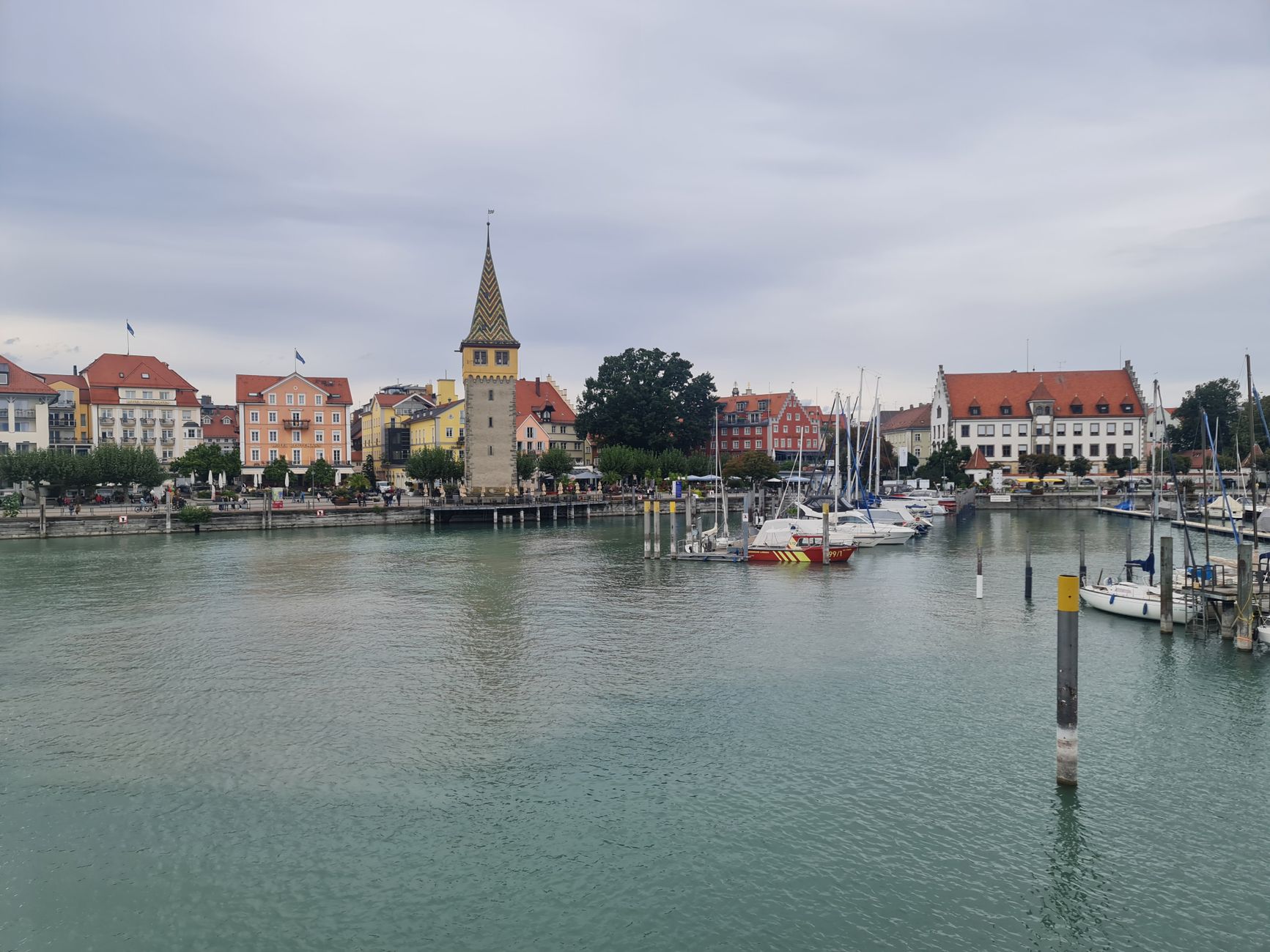 Charming view of Lindau harbor featuring colorful houses, Mangturm tower, and docked boats on Lake Constance.