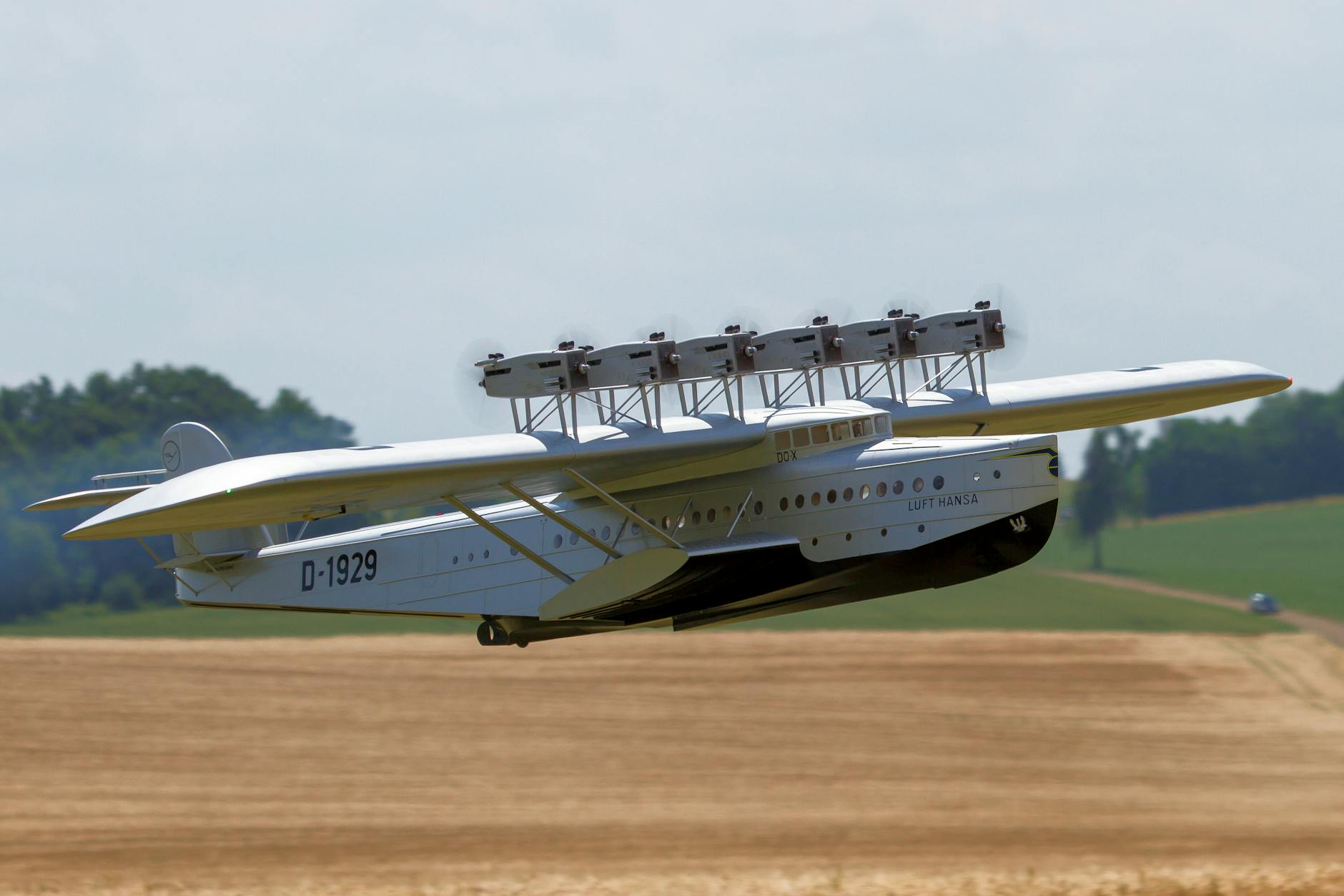 A classic biplane flying over a rural landscape, showcasing vintage aviation technology.